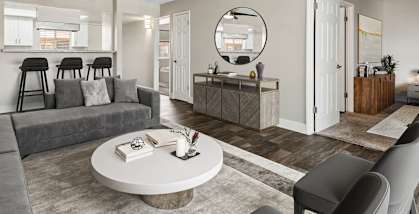 Model Living Room with Wood-Style Flooring and View of Kitchen at Villages at Metro Center located in Phoenix, AZ-HERO.