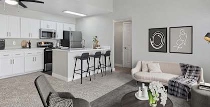 Model Living Room with Carpet and View of Kitchen with Wood-Style Flooring at Crystal Creek Apartments in Phoenix, AZ-HERO.