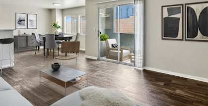 Model Living Room with Wood-Style Flooring, View of Dining Room & Patio Accessibility at Loma Vista Apartments in Las Vegas, NV-HERO.