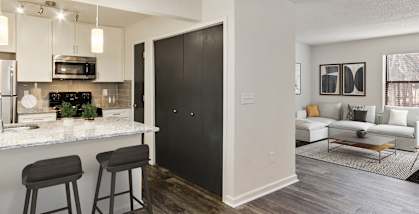 Model Kitchen with White Cabinets and Wood-Style Flooring at Grandstand Apartments in Marietta, GA-HERO.