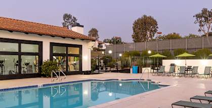 A pool with lounge chairs and umbrellas outside a building.