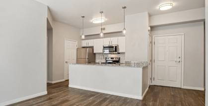 Model Kitchen with Wood-Style Flooring, White Cabinets, and Stainless-Steel Appliances at Altitude on Fifth Apartments located in Salt Lake City, UT.