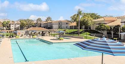 A large swimming pool surrounded by a fence and lounge chairs.