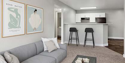 Model Living Room with Carpet and View of Kitchen at Stonegate Apartments located in Las Vegas, NV-HERO.