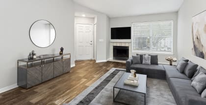 Model Living Room with Wood-Style Flooring and View of Kitchen at Retreat at Crosstown Apartments in Riverview, FL-HERO.