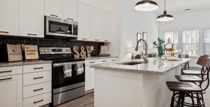 Model apartment kitchen with a large counter top and a sink