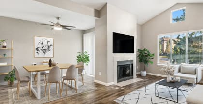 Model apartment living room with a fireplace and a dining room table