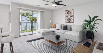Model living room with a white couch and a ceiling fan at Waverley Place Apartments in Naples, Florida