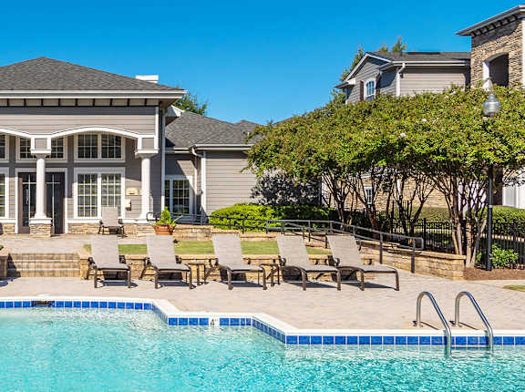 a swimming pool with lounge chairs and umbrellas in front of a building
