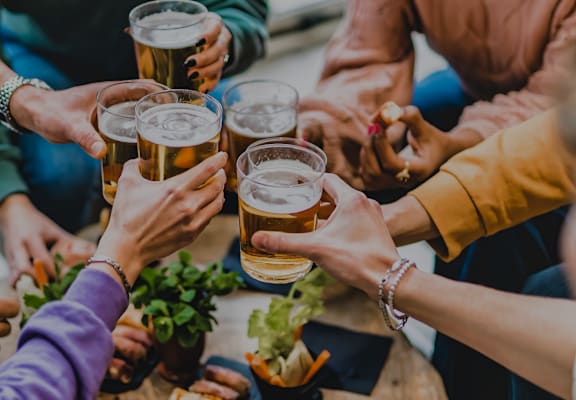 A group of people toasting with beer glasses at a table.