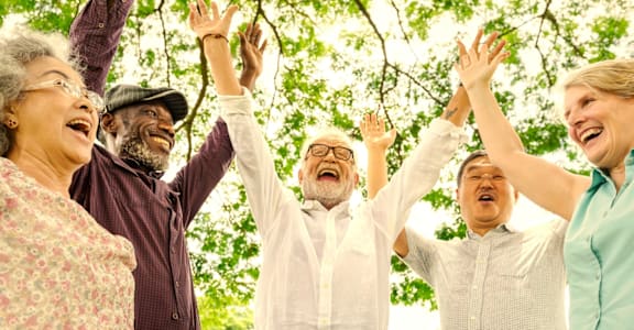 A group of people are standing together with their arms raised.