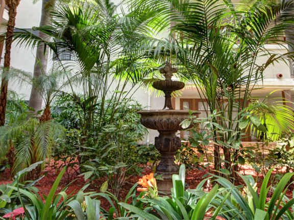A large atrium with a fountain and a balcony at Darlington Apartments, Los Angeles, CA