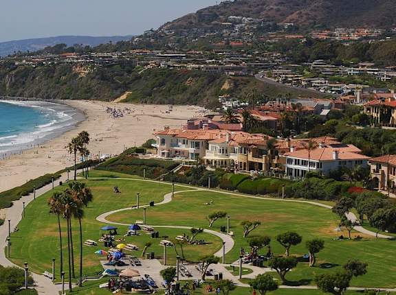 A beach with people on it and a building in the distance at The Villas at Monarch Beach, Dana Point, CA