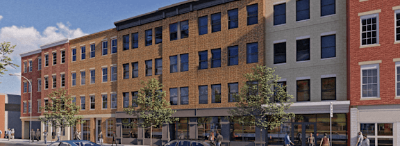 A street view of a multi-story building with cars parked in front.