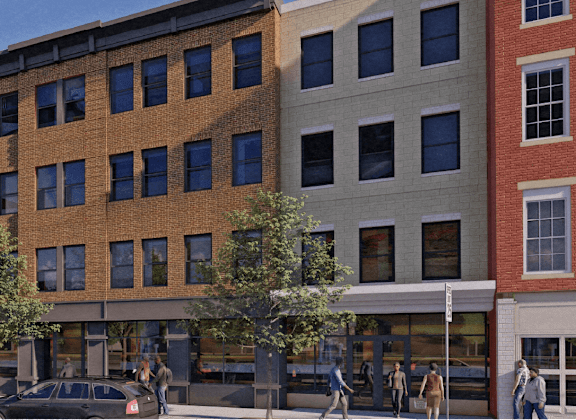 A street view of a multi-story building with cars parked in front.