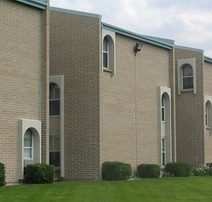 A large brick building with arched windows and a green roof.
