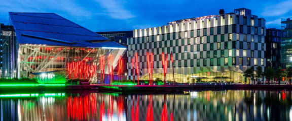 a glass building with palm trees in front of it
