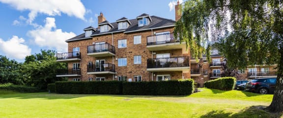 a brick apartment building with a lawn and a tree