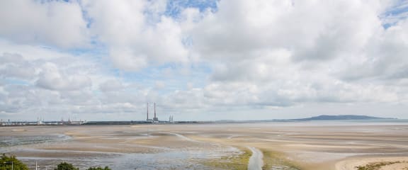 a view of a beach with a power plant in the background