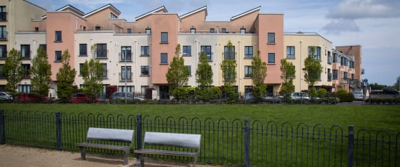 a row of houses with benches in front of a green field