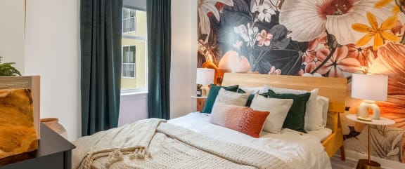 a bedroom with a bed with pillows and a mural on the wall