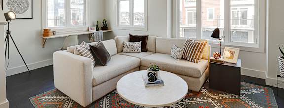 A living room with a white couch and a round table in the middle.