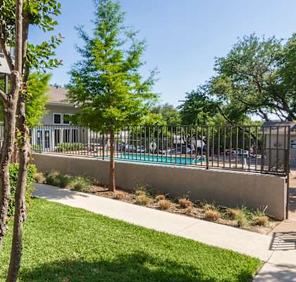 a yard with a pool and a building with a fence  at The Biltmore, Dallas, Texas