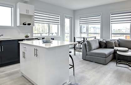 A modern kitchen with a white island and black cabinets.