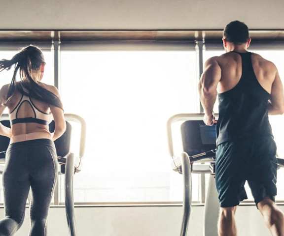 a man and a woman are looking out the window at the gym