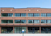 Thumbnail 1 of 7 - A large red brick building with a flat roof and a blue sign on the ground. at The Mobile Lofts, Alabama