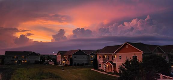 A row of houses are seen in front of a dramatic sky.