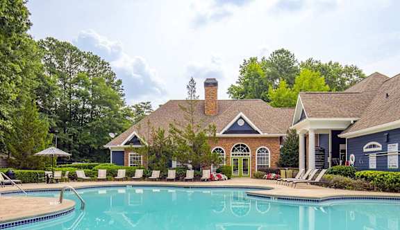 A large swimming pool in front of a house with a blue roof.