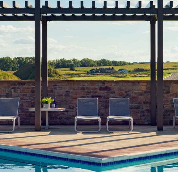 a swimming pool with chairs and a table next to it