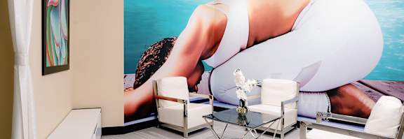 A woman in a white bikini is on a large poster in a room with white chairs and a coffee table.