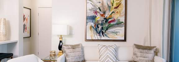 A white couch with a gold frame and a painting above it.
