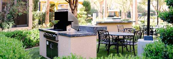 A patio with a grill and chairs.