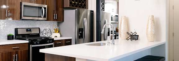 A kitchen with a white counter top and a stove top oven.