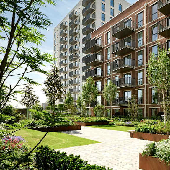 A modern apartment complex with a landscaped garden in front.