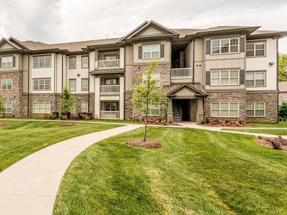 an exterior view of an apartment building with a sidewalk