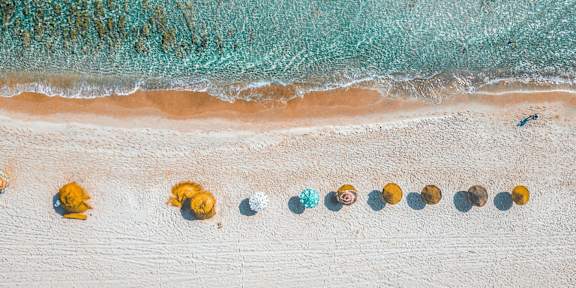 A beach with a line of yellow and blue objects on the sand.