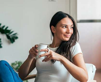 a woman sitting in a chair holding a cup of coffee