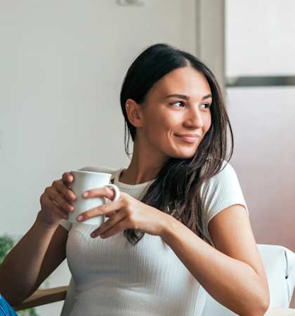a woman sitting in a chair holding a cup of coffee