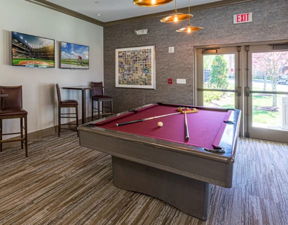 A pool table is in the middle of a room with chairs and pictures on the wall at Axis at Lakeshore Apartments, Bridgewater, Massachusetts