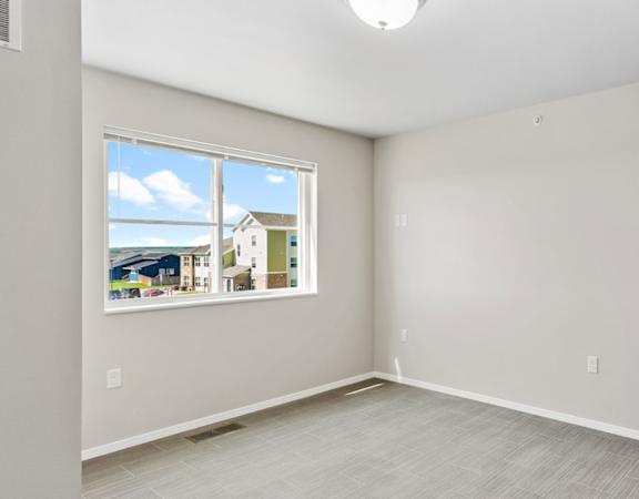 an empty living room with a window and white walls