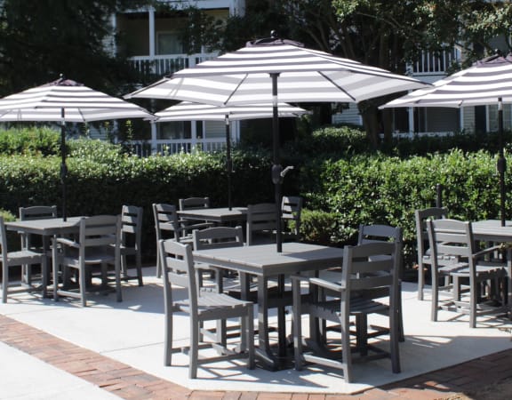 picnic tables with shady umbrellas surrounded by lush landscaping