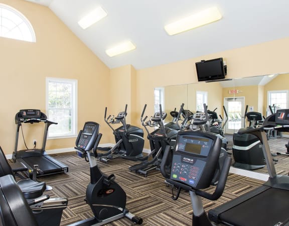 a gym with various exercise bikes and a tv