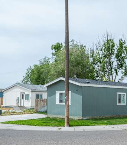 A grey house with a green lawn in front.