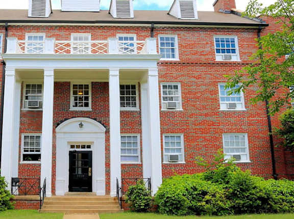 a red brick building with white columns and a black door
