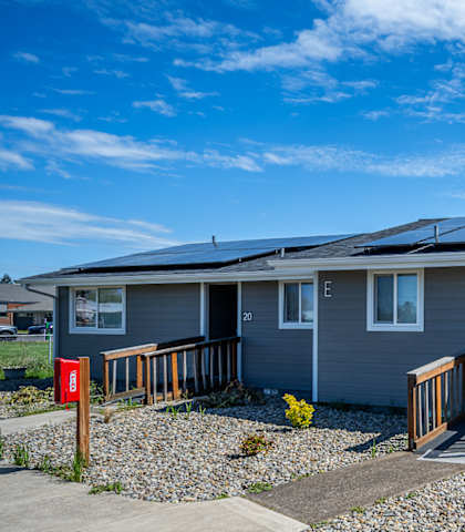 A house with a grey roof and a red mailbox.