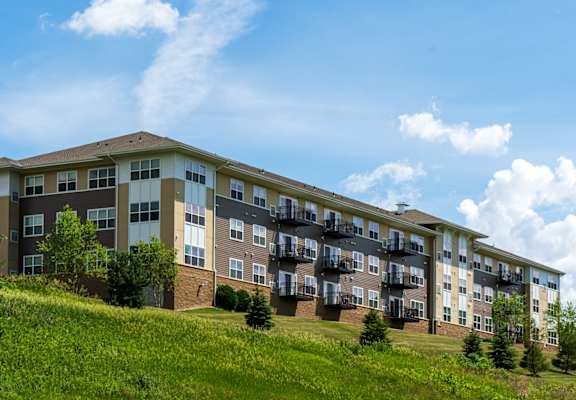 an apartment building on a grassy hill with a blue sky in the background